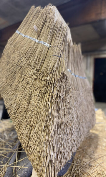 A sculpture created using traditional thatching techniques, where densely packed straw is shaped into a geometric structure.