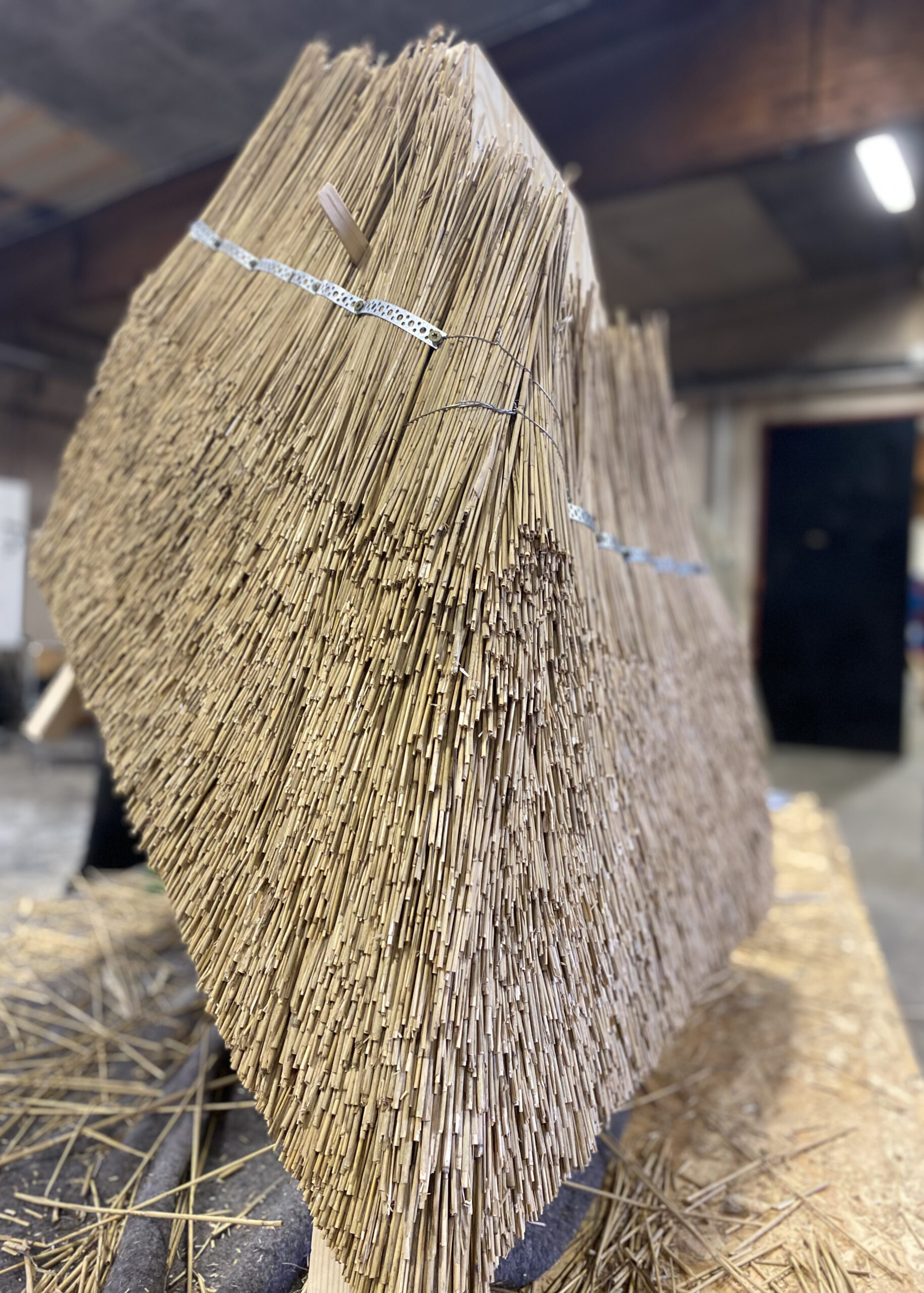 A sculpture created using traditional thatching techniques, where densely packed straw is shaped into a geometric structure.
