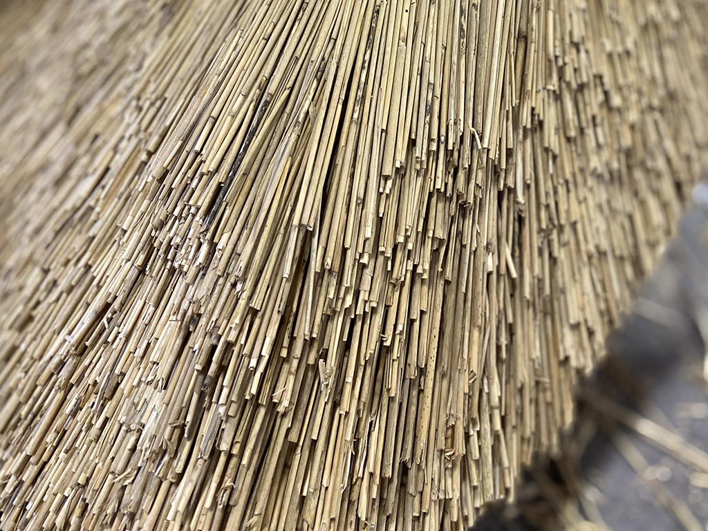 A sculpture created using traditional thatching techniques, where densely packed straw is shaped into a geometric structure.