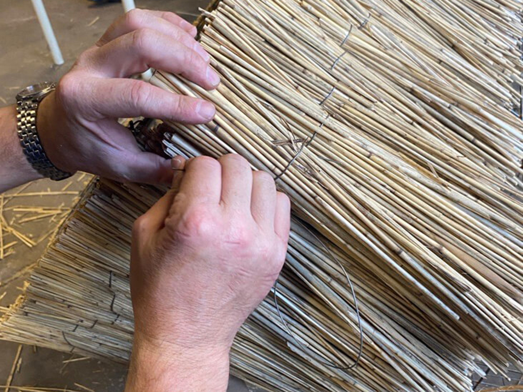 A sculpture created using traditional thatching techniques, where densely packed straw is shaped into a geometric structure.