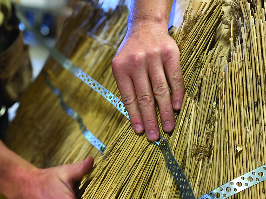 A sculpture created using traditional thatching techniques, where densely packed straw is shaped into a geometric structure.