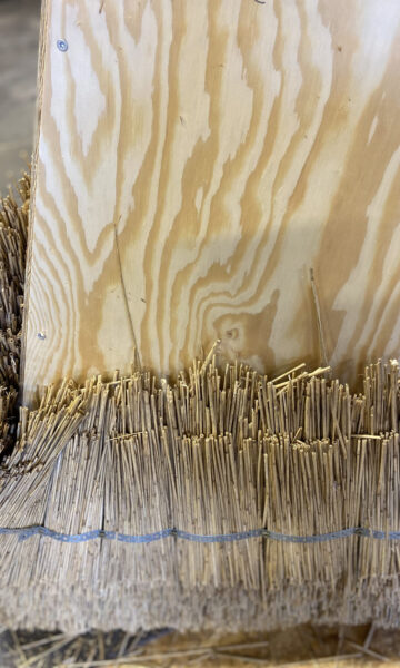 A sculpture created using traditional thatching techniques, where densely packed straw is shaped into a geometric structure.