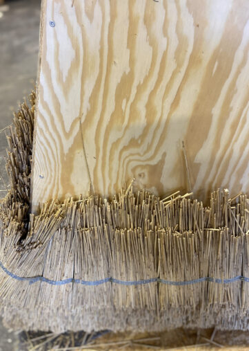 A sculpture created using traditional thatching techniques, where densely packed straw is shaped into a geometric structure.