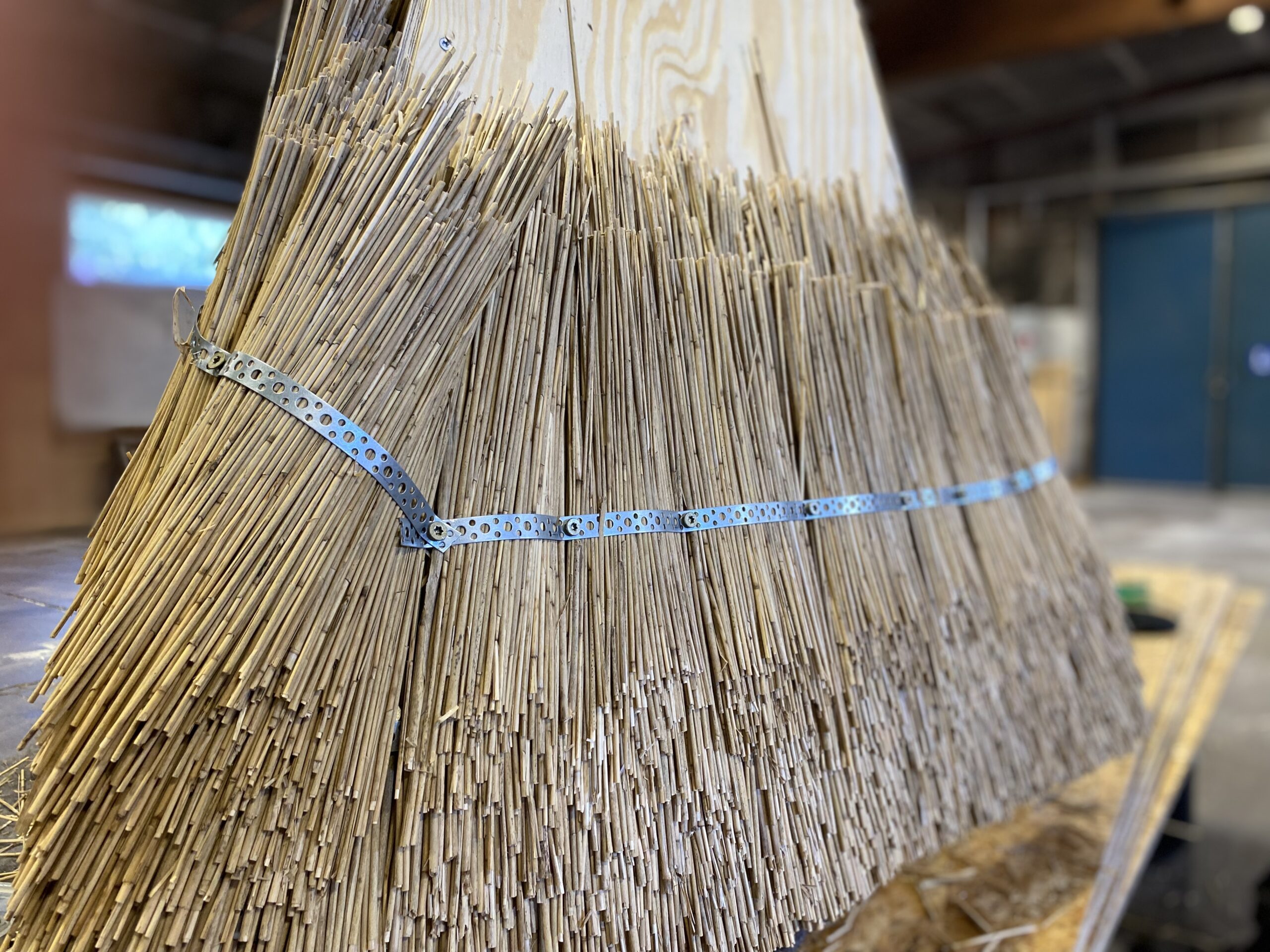 A sculpture created using traditional thatching techniques, where densely packed straw is shaped into a geometric structure.