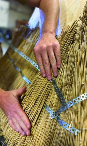 A sculpture created using traditional thatching techniques, where densely packed straw is shaped into a geometric structure.